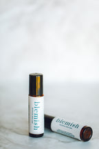 Roll-on bottle labeled 'blemish' on a marble surface with a white background