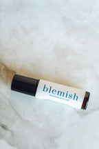 acne essential oil Roll-on bottle labeled 'blemish' on a marble surface