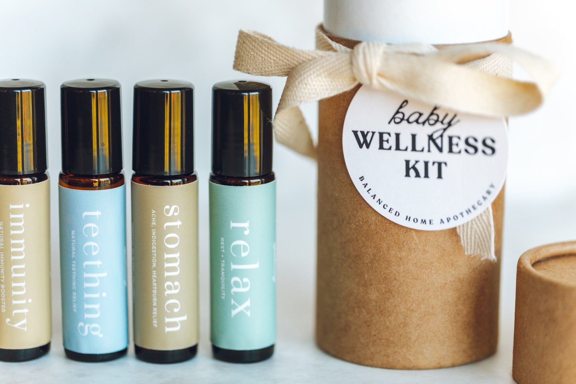 Set of roller bottles labeled 'immunity', 'teething', 'stomach', 'relax' with a 'baby wellness kit' container.